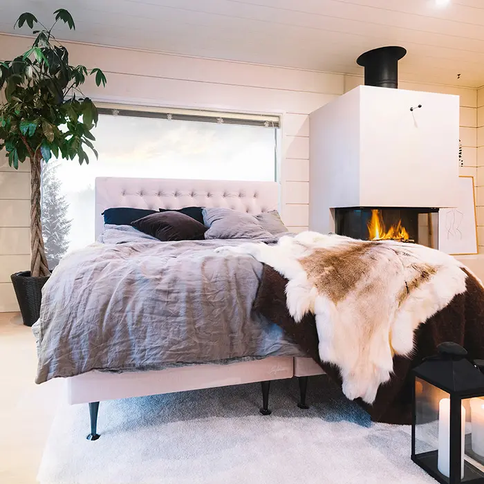 Muhkea jenkkisänky sisustettuna moderniin mökkiin takkatulen äärelle.